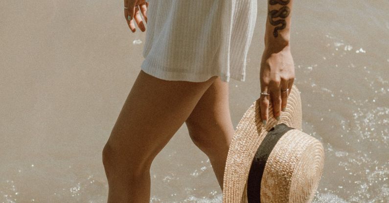 Neutral Colors - Woman in White and Blue Stripe Skirt and Brown Sun Hat Standing on Water