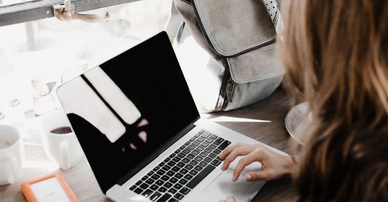 Productive Workspace - Close-up Photography of Woman Sitting Beside Table While Using Macbook